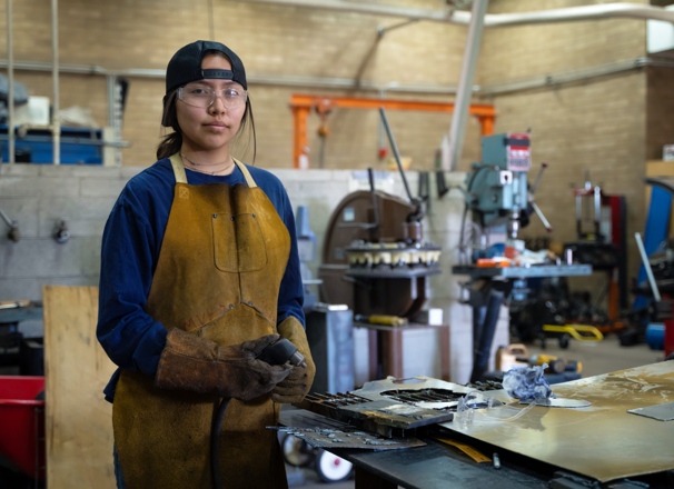 Young person working on sheet metal in a shop.